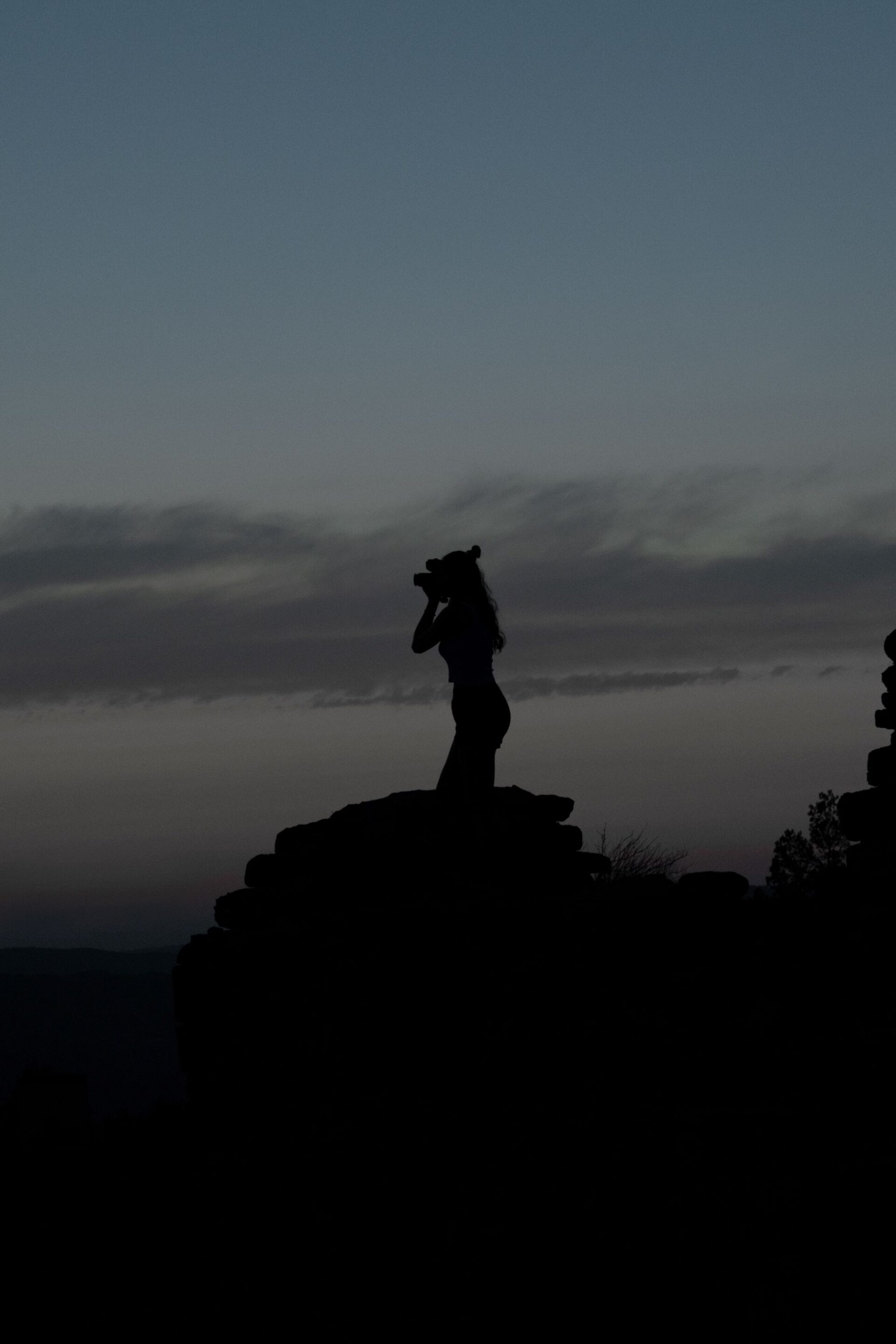 Silueta d'una fotògrafa fent una fotografia durant el capvespre, en un entorn natural i fosc, fotografia nocturna a la natura. Foto nocturna a la Muntanya de Montserrat.