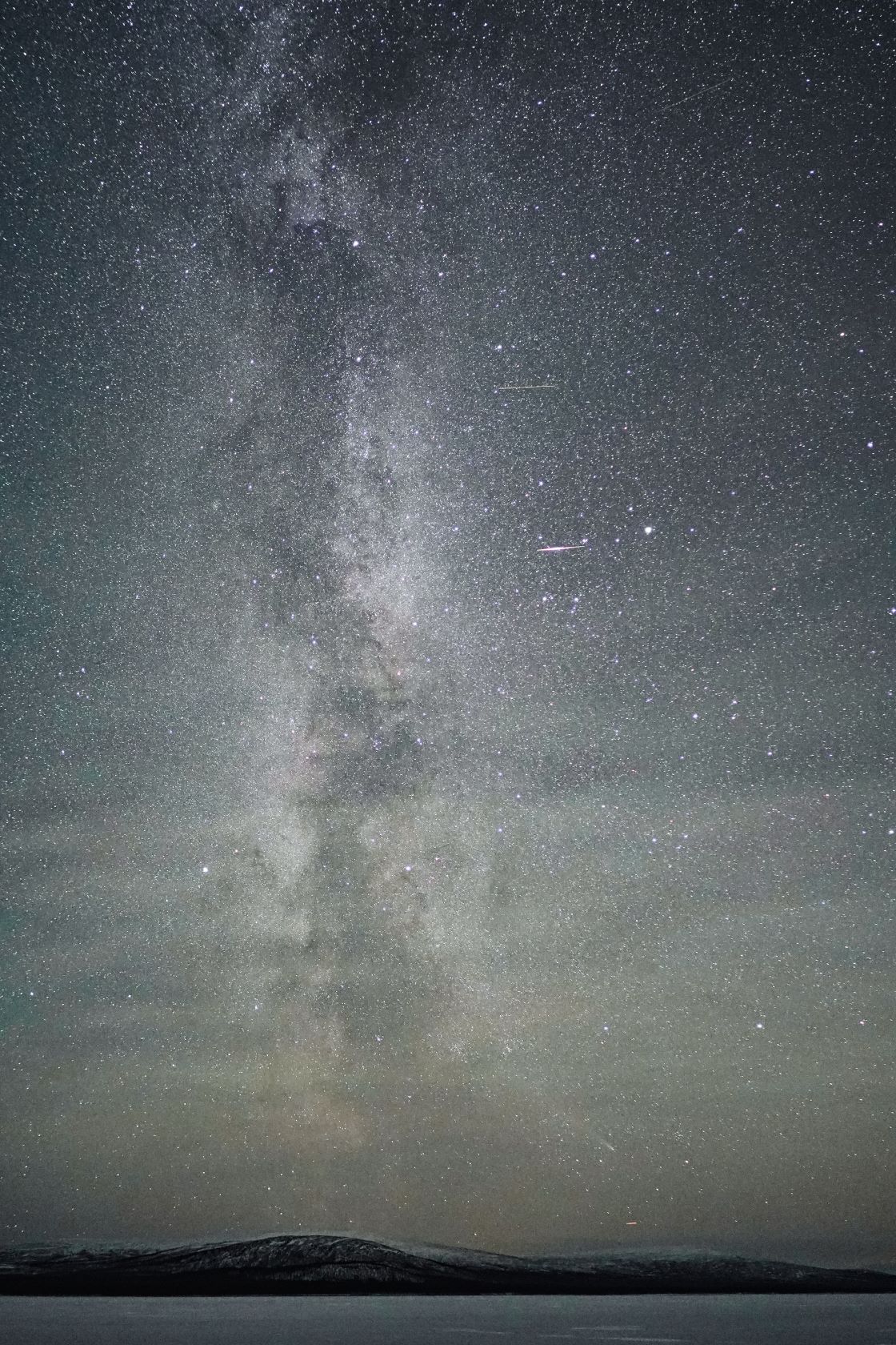 Via Làctia sortint verticalment de l’horitzó amb un estel fugaç al cel nocturn, fotografia astronòmica feta a l'àrtic.