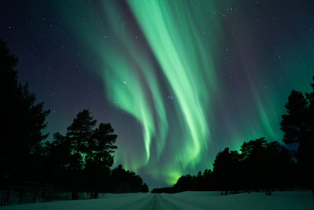 Carretera Nikkaluokta coberta de neu amb aurora boreal al cel.