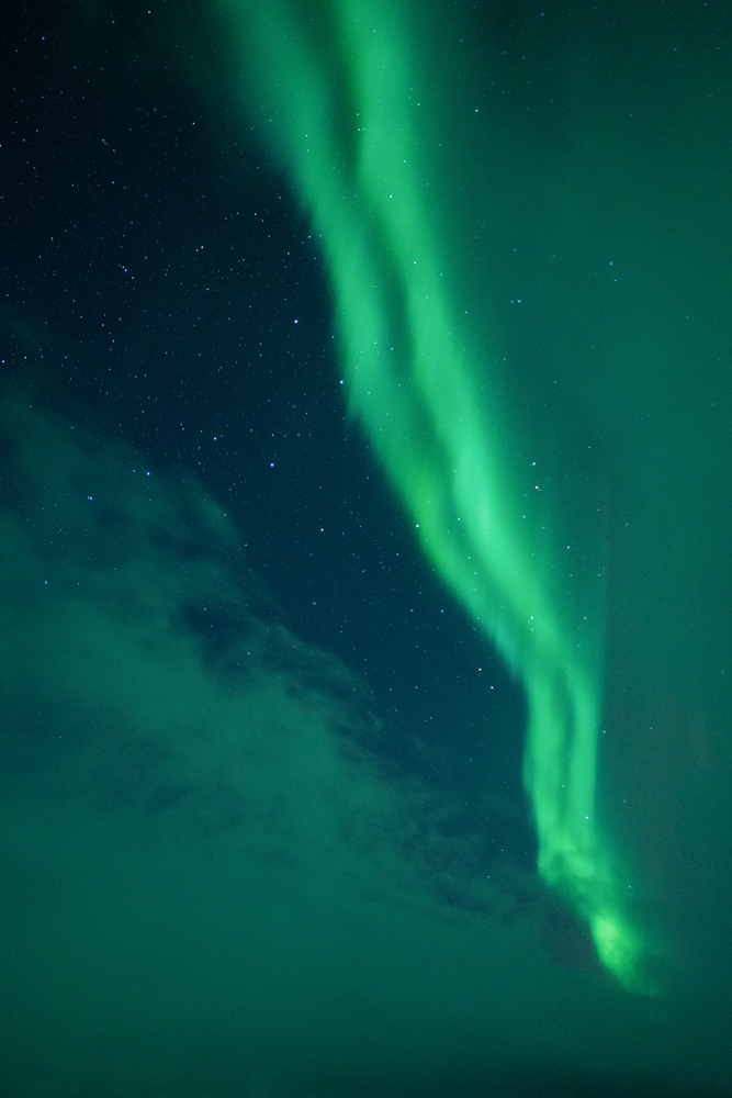 Cel dividit entre núvols i aurora boreal en línia vertical, a Abisko, Suècia.