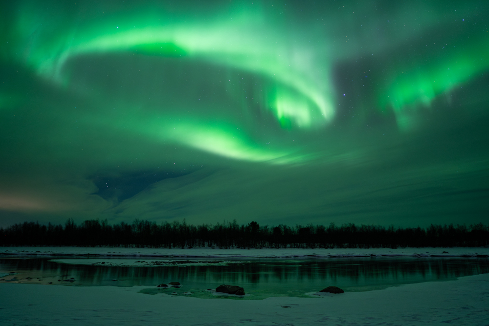 Aurora boreal en forma circular reflectida sobre llac gelat, a Kiruna, Lapònia sueca.