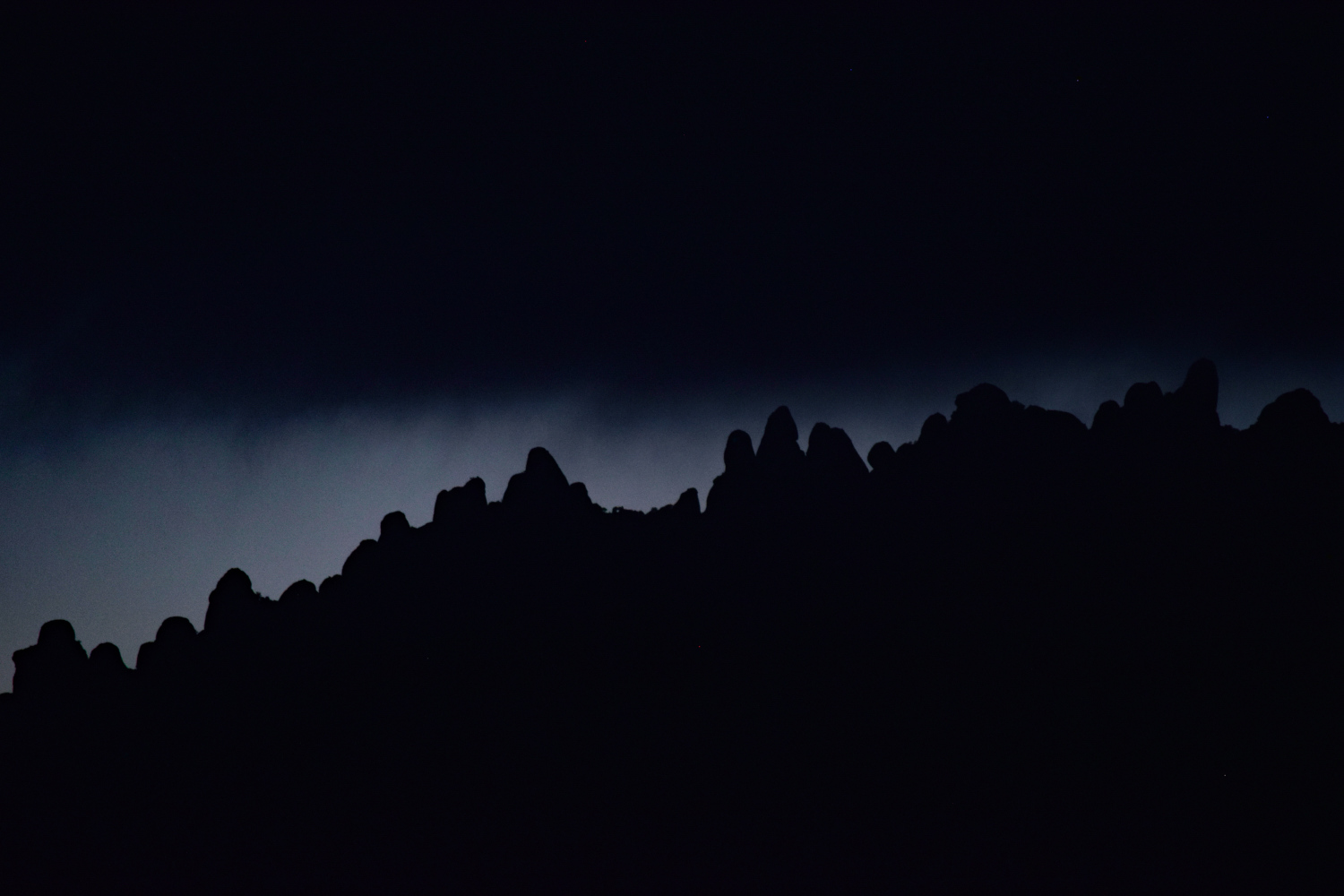Silueta de les agulles de Montserrat en un capvespre ennuvolat, just abans de fer-se fosc.