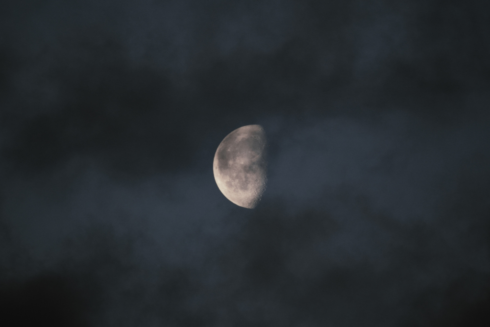 Lluna en quart minvant emergint entre els núvols durant la nit.